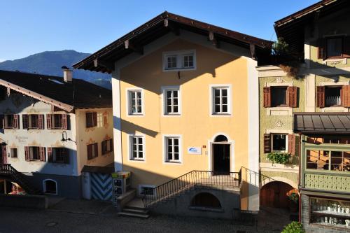 a yellow house in the middle of two other buildings at Appartements Altes Gericht in Hopfgarten im Brixental