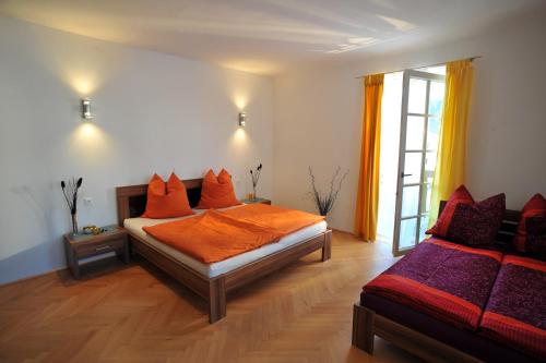 una camera da letto con un letto con lenzuola arancioni e una finestra di Appartements Altes Gericht a Hopfgarten im Brixental