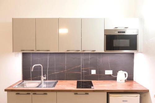 a kitchen with white cabinets and a sink at Sands Apartments in St Paul's Bay