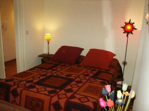 リスボンにあるカーザス ド バイロアルトの赤い枕と花のベッド付きのベッドルーム1室