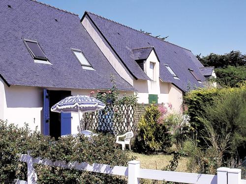 una casa con una sombrilla y una silla delante de ella en Lagrange Vacances Les Maisonnettes, en Le Pouliguen