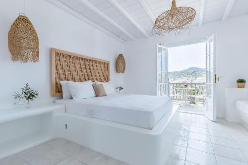 a white bedroom with a large bed and a tub at Evlalia Studios & Villas in Skopelos Town