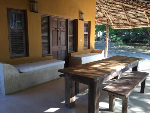 a wooden table and bench in front of a house at Mangrove House in Lamu