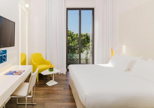 a white bed sitting next to a window in a room at H10 Urquinaona Plaza in Barcelona