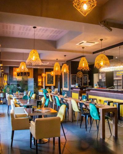 a restaurant with tables and chairs and chandeliers at Le Safari Hotel Restaurant in Carpentras