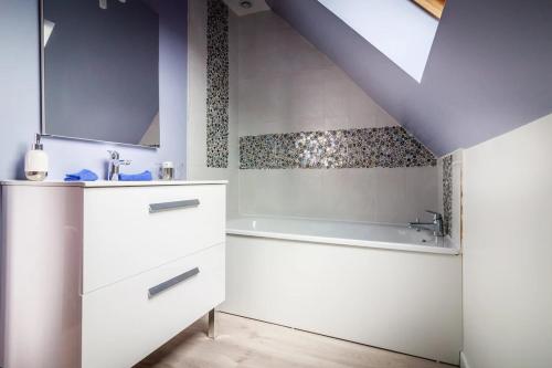 a bathroom with a white sink and a bath tub at Le Verger du Mesnil in Le Mesnil-Réaume
