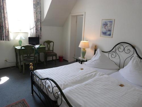 a bedroom with a bed and a desk with a laptop at Hotel Jägerhof in Mayen