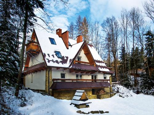 ein Haus mit schneebedecktem Dach im Schnee in der Unterkunft APARTAMENTY SOBICZKOWA WYSPA in Kościelisko
