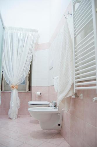 a bathroom with a toilet and a white curtain at B&B Villa Roma in Piazza Armerina
