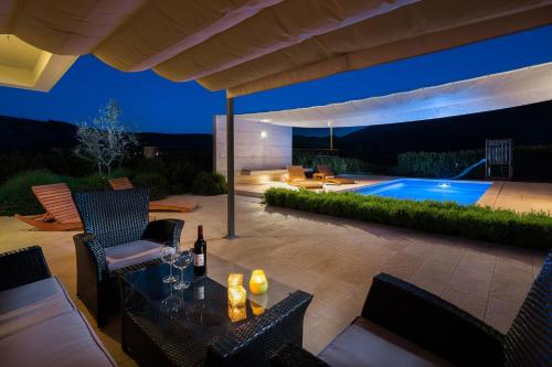 a patio with a table and chairs and a swimming pool at Luxury villa Wisdom near Split, private pool in Dugopolje