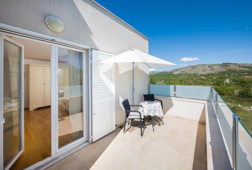 a balcony with a table and chairs and an umbrella at Luxury villa Wisdom near Split, private pool in Dugopolje