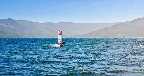 a small sail boat in the middle of the water at Complejo Pehuen Lago Lanalhue in Cañete