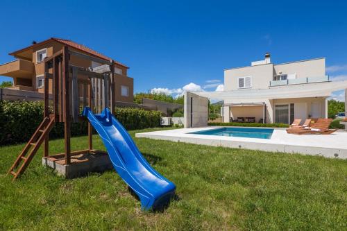 a blue slide in a yard in front of a house at Luxury villa Wisdom near Split, private pool in Dugopolje