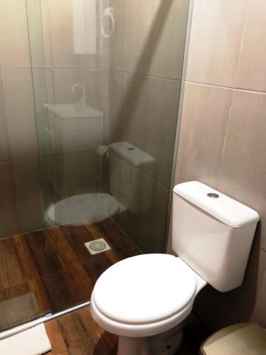 a bathroom with a white toilet and a shower at Pousada Esperança in Osório