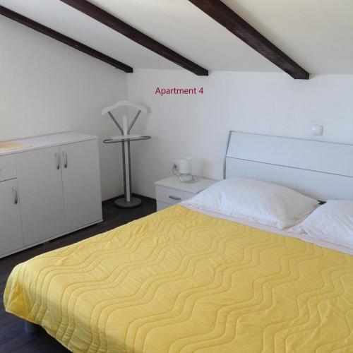a bedroom with a bed with a yellow blanket at Apartment One in Rab