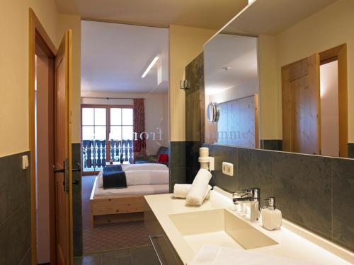 a bathroom with a sink and a bedroom with a bed at Hotel Garni Frommes in Fiss
