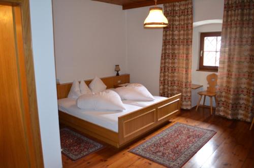 Un dormitorio con una cama con almohadas blancas y una ventana en Ansitz Goller, en Rasun di Sopra