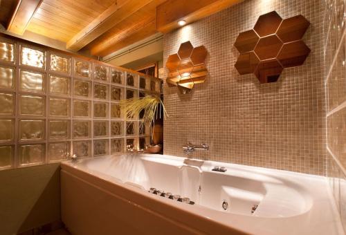 a bathroom with a tub and a tiled wall at La Pausa Rural & Wellness in Santa Greu del Jutglar