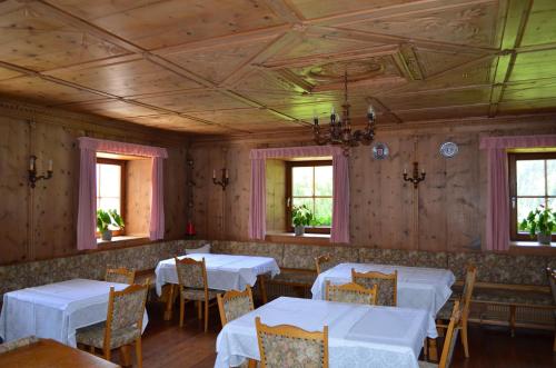 un comedor con mesas y sillas blancas y ventanas en Ansitz Goller, en Rasun di Sopra