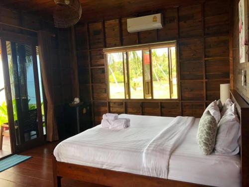 a bedroom with a large white bed with a window at Itsara bungalow in Surat Thani