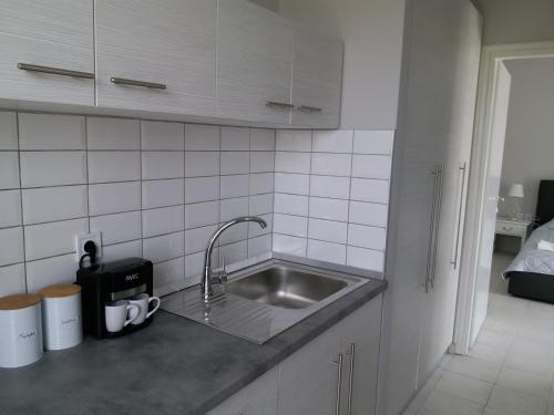 un bancone della cucina con lavandino e piastrelle bianche di SIMPLICITY a Marmári