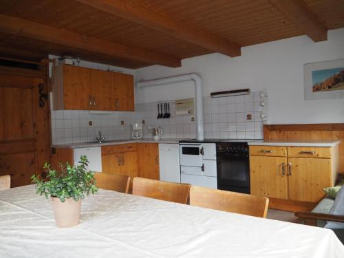 una cocina con armarios de madera y una mesa con una maceta. en Ferienhaus Innerkienzerhof - Urlaub am Bauernhof, en Matrei in Osttirol