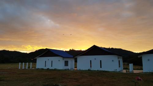 a group of buildings in a field at sunset at Halcyon Days @ Langkawi in Pantai Cenang