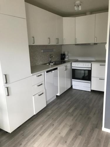 a kitchen with white cabinets and a wooden floor at Fjordgård Leilighet A in Fjordgård