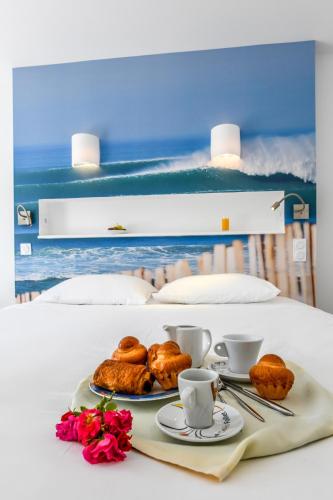 a table with two plates of pastries and coffee cups at Les Vagues Hôtel Restaurant in Biscarrosse-Plage