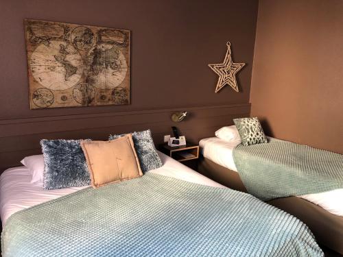 a room with two beds and a map on the wall at Logis Hôtel Burnichon in Tarare