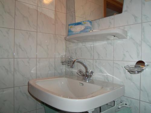 a white sink in a white tiled bathroom at Hotel Schwarzer Adler in Pettneu am Arlberg