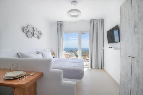 a white bedroom with a bed and a view of the ocean at Sea & Stone Residence Mykonos in Platis Yialos Mykonos