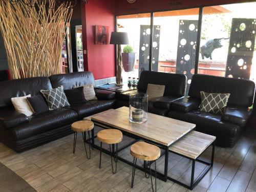 a living room with black leather furniture and a table at Logis Hôtel Burnichon in Tarare