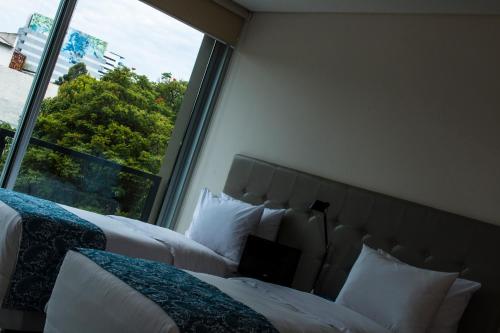 two beds in a room with a large window at START Villa Morra Rent Apartments in Asuncion
