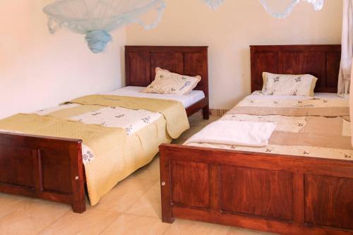 two beds in a room with wooden furniture at Hotel Atlantica in Fort Portal