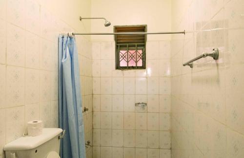 a bathroom with a shower with a toilet and a window at Hotel Atlantica in Fort Portal