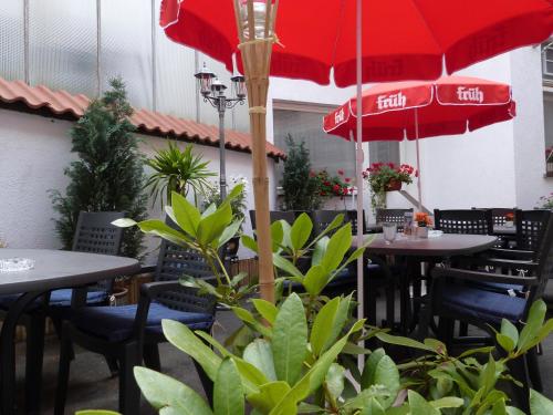 a restaurant with tables and chairs with red umbrellas at Hotel Jägerhof in Mayen