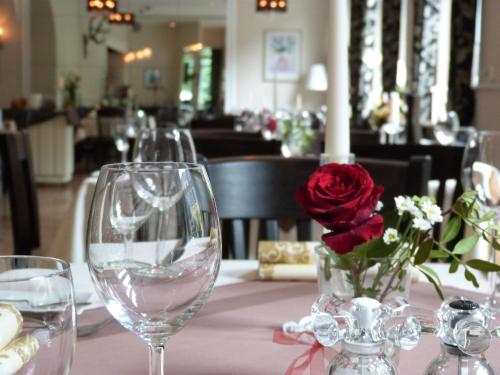 a table with wine glasses and a vase with a red rose at Hotel Jägerhof in Mayen