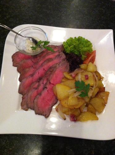 a white plate with a piece of steak and potatoes at Hotel Jägerhof in Mayen