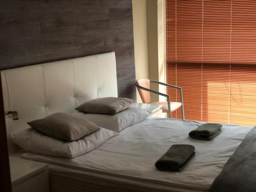 ein Bett mit zwei Kissen und einem Stuhl neben einem Fenster in der Unterkunft Komfortowe Apartamenty in Okuninka