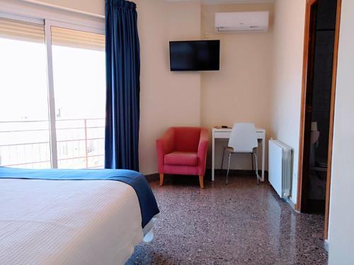 a bedroom with a bed and a desk with a red chair at Hotel Ramis fundado en 1969 in Ondara