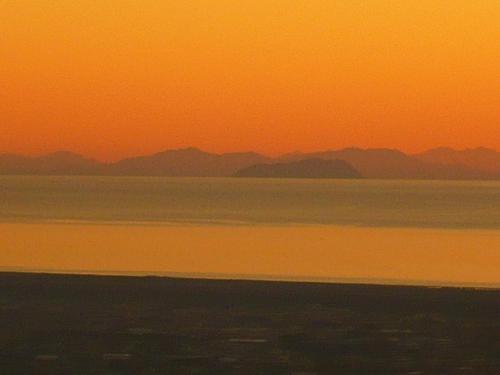 a sunset over the water with mountains in the background at Le Ginestre B & B in Massarosa