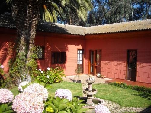 a red house with flowers in front of it at Posada del Parque in Concón