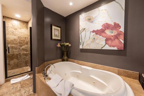 a bathroom with a tub and a painting of flowers at A Sunset Chateau in Sedona