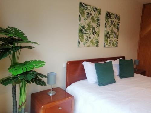 a bedroom with a bed with green pillows and a plant at Lemon Tree Apartment in Vila do Conde