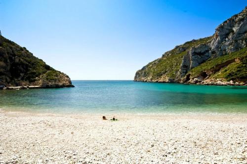 two people sitting on a beach near the ocean at Royal Garden Santa Clara in Jávea