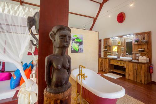 a bathroom with a statue of a person next to a tub at Villa Raymond, Diani, Kenya in Diani Beach