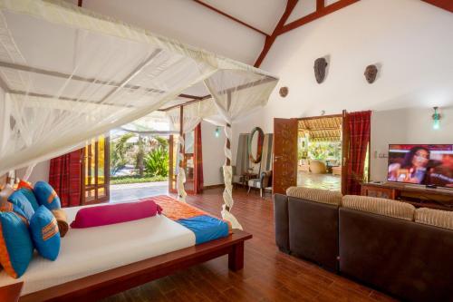a living room with a bed and a tv at Villa Raymond, Diani, Kenya in Diani Beach