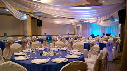 una habitación llena de mesas y sillas con manteles azules en Hotel Monteolivos, en San Pedro Sula