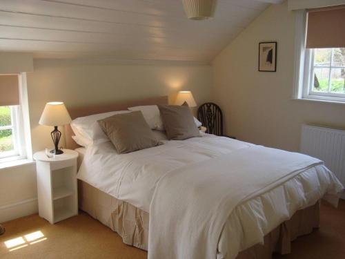 a bedroom with a large white bed with two windows at Stunning 3 bedroom self catering cottage near Stonehenge, Salisbury, Avebury and Bath All bedrooms ensuite in Pewsey